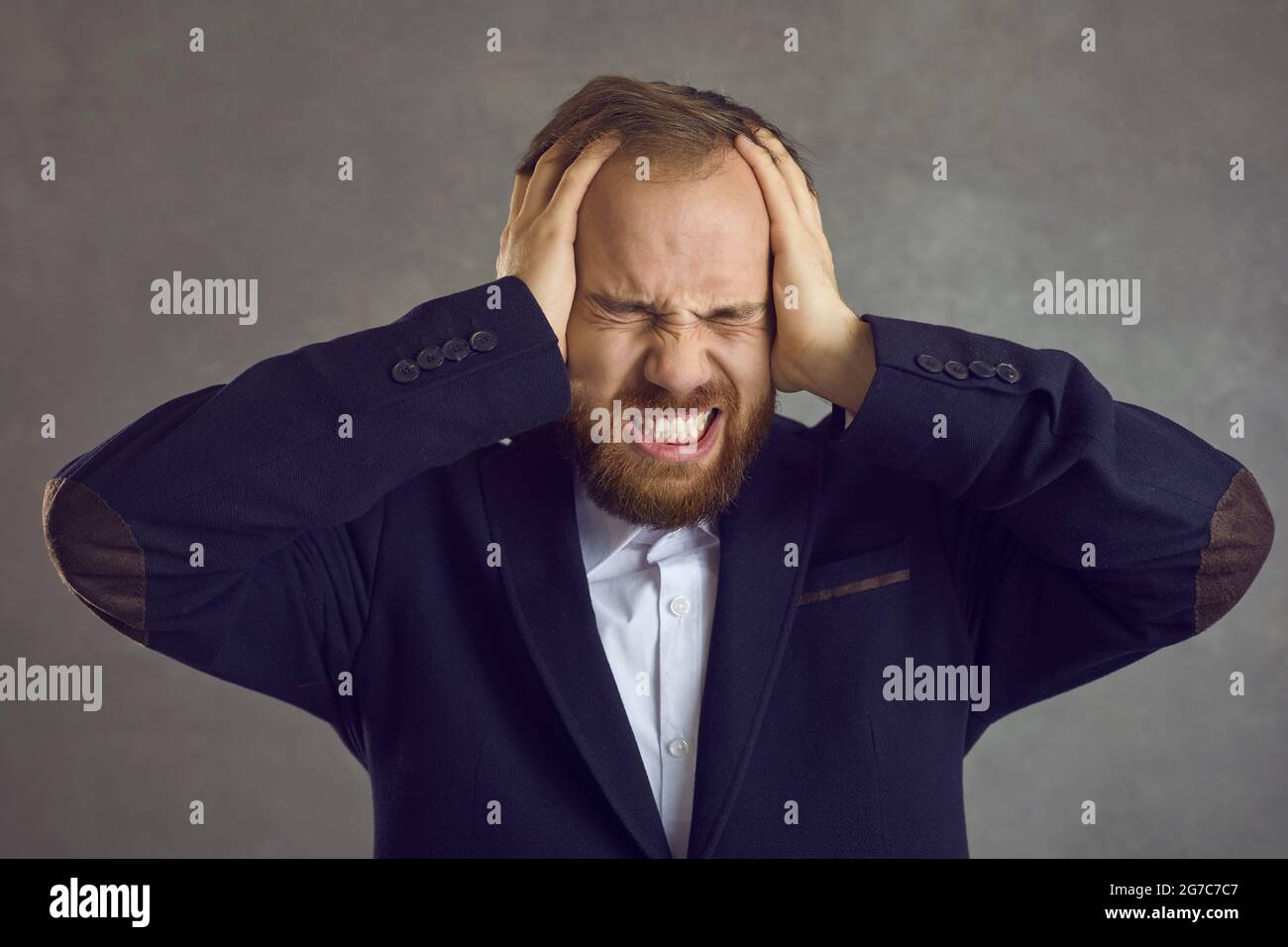 Stressed annoyed man covers his ears with his hands protecting from a loud noise Stock Photo