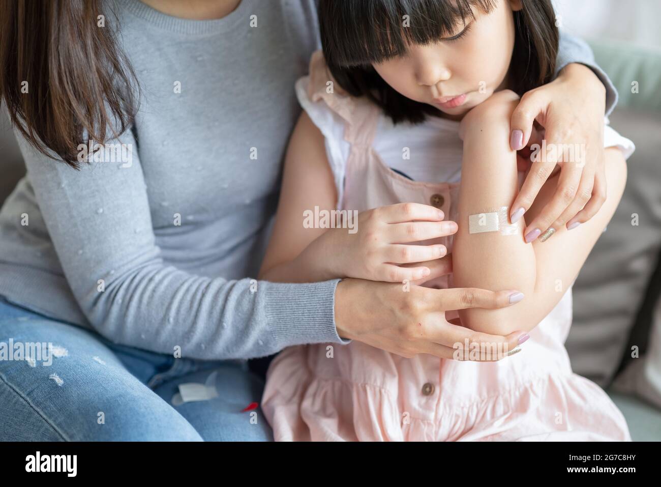 Asian mother putting court plaster adhesive bandage onto her daughter at home Stock Photo