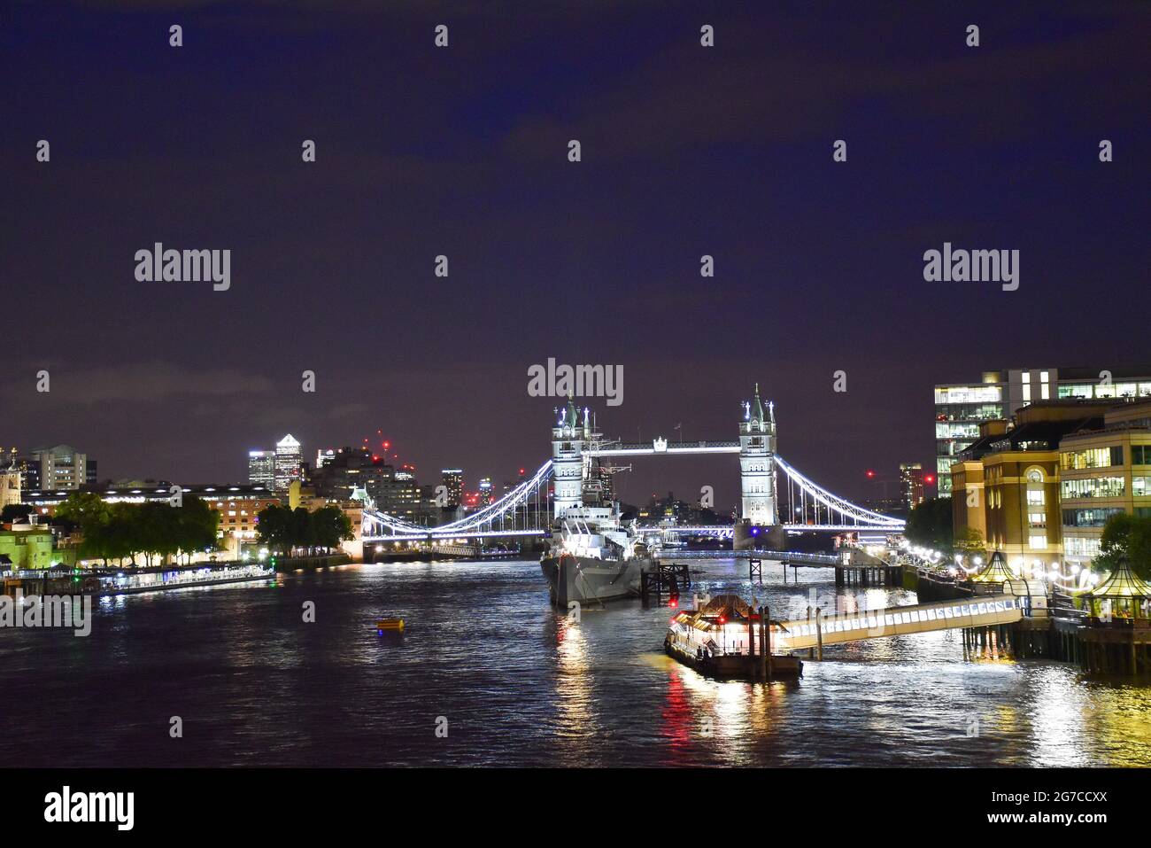 View of the River Thames at night with the illuminated London Bridge and HMS Belfast. Stock Photo