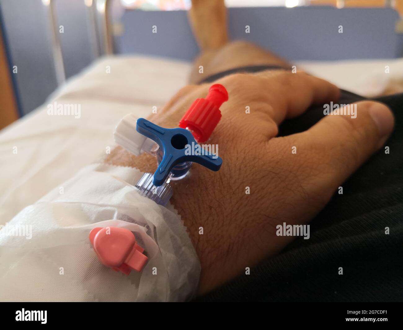 Close-up of the needle cannula in the arm of a patient lying on a hospital bed Stock Photo