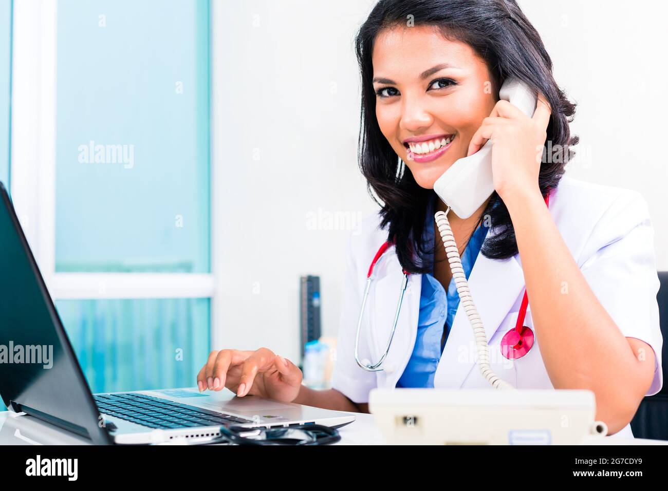 Asian female doctor working and telephoning in office or medical practice Stock Photo