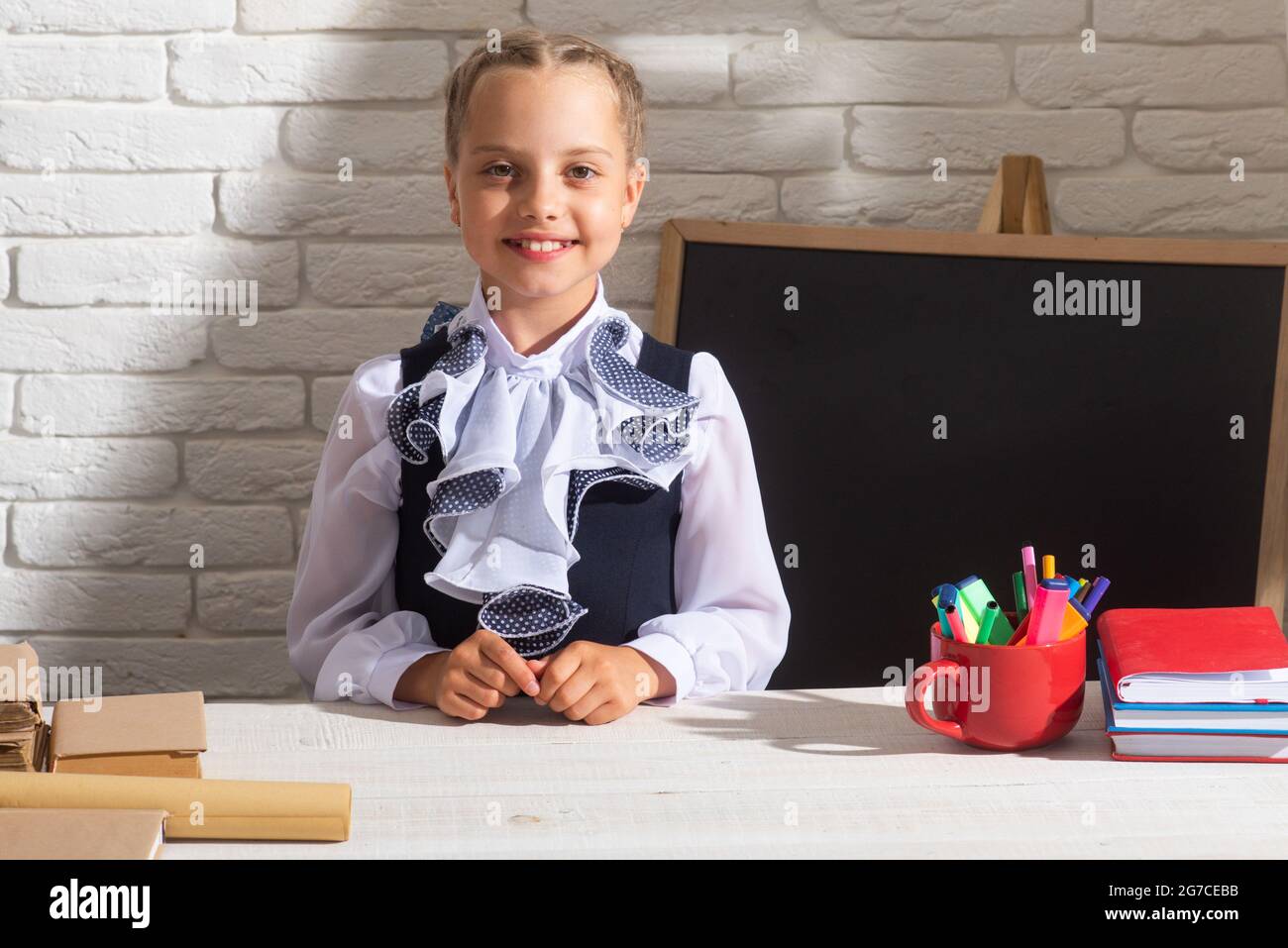 Smiling school girl wearing school uniform in classroom at school ...
