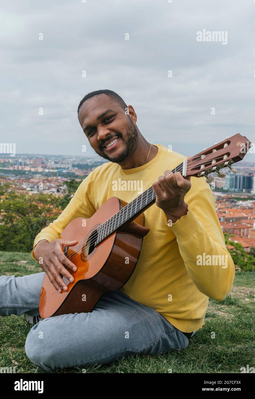 Black man playing guitar in an outdoor park Stock Photo