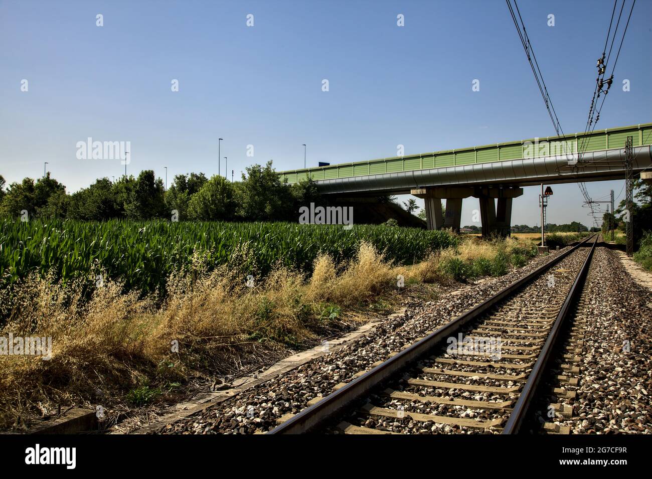 Railroad track that passes under a viaduct in the italian countryside in summer Stock Photo