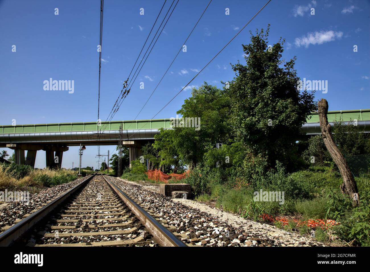 Railroad track that passes under a viaduct in the italian countryside in summer Stock Photo