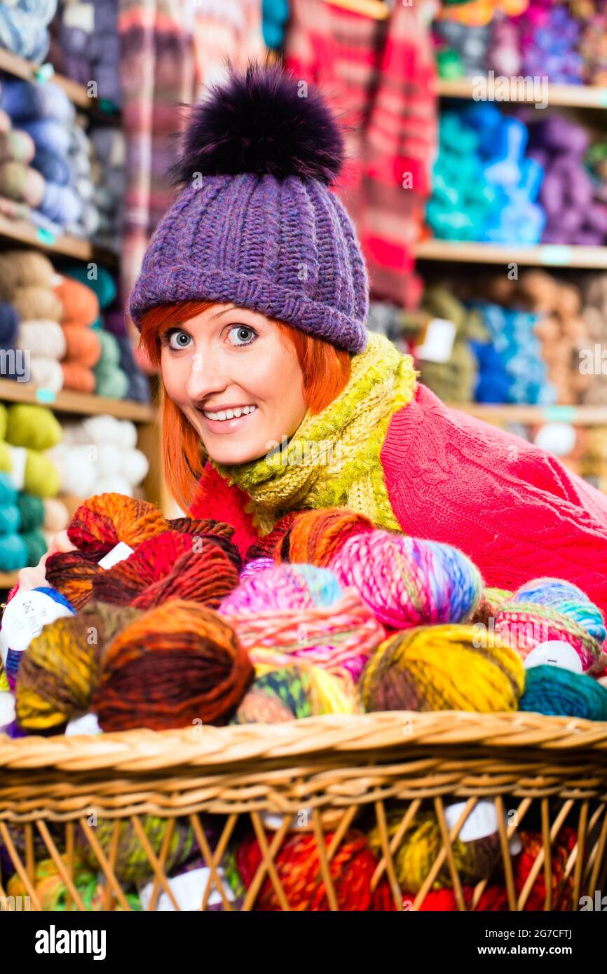 Young woman buying colorful wool and yarn for their hobby in a knitting shop Stock Photo