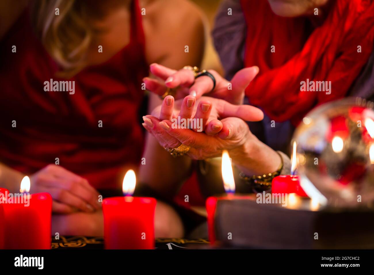 Female Fortuneteller or esoteric Oracle, sees in the future by hand reading during a Seance to interpret them and to answer questions Stock Photo