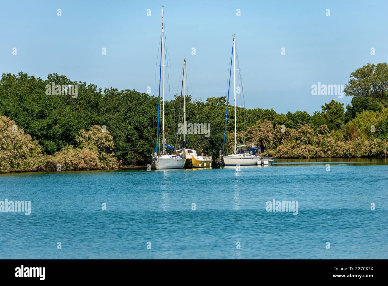 Two sailing boats and a catamaran moored in the Venetian lagoon near the small Burano Island, Venice, Veneto, Italy, Europe. Stock Photo