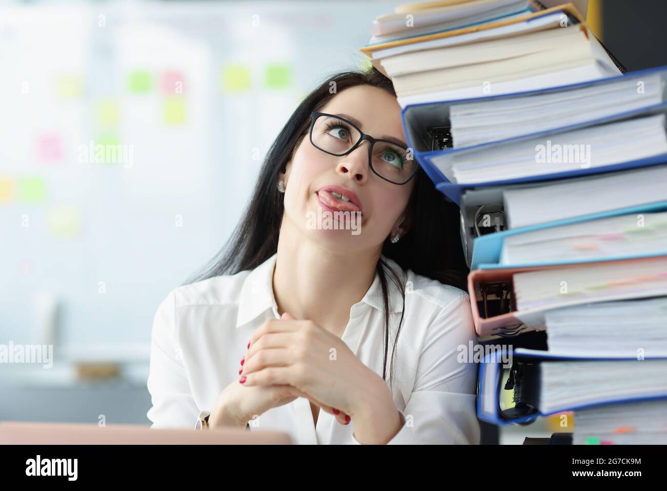 Tired young woman sitting at desk with lot of documents closeup Stock Photo