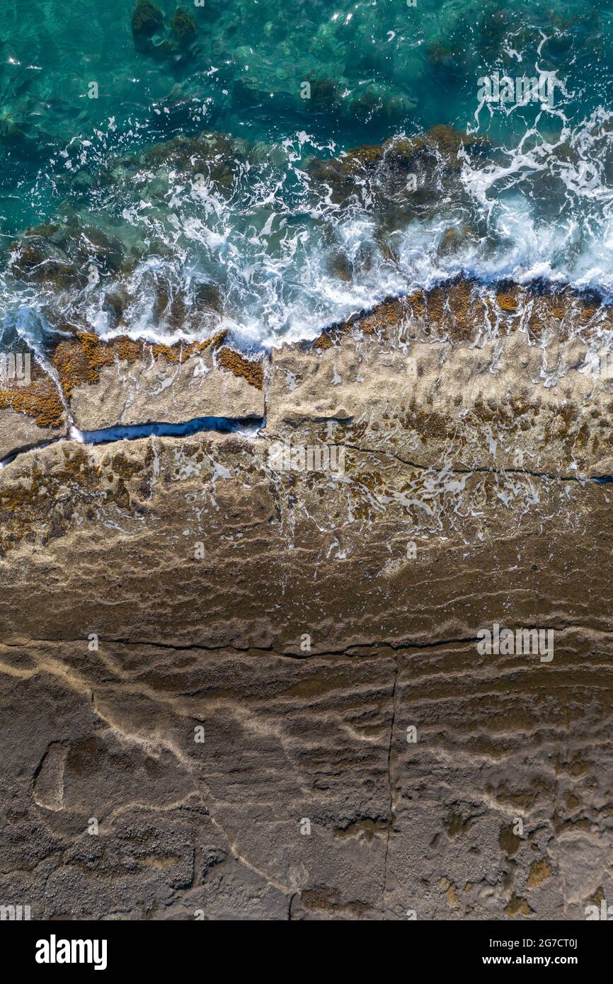 Sea waves breaking on rocky shore, aerial vertical shot directly above Stock Photo