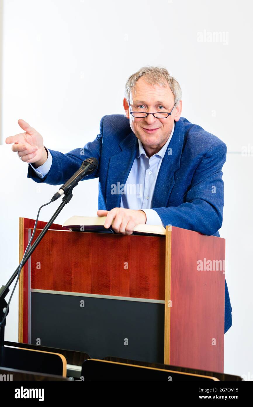 College professor giving lecture and standing at desk Stock Photo - Alamy