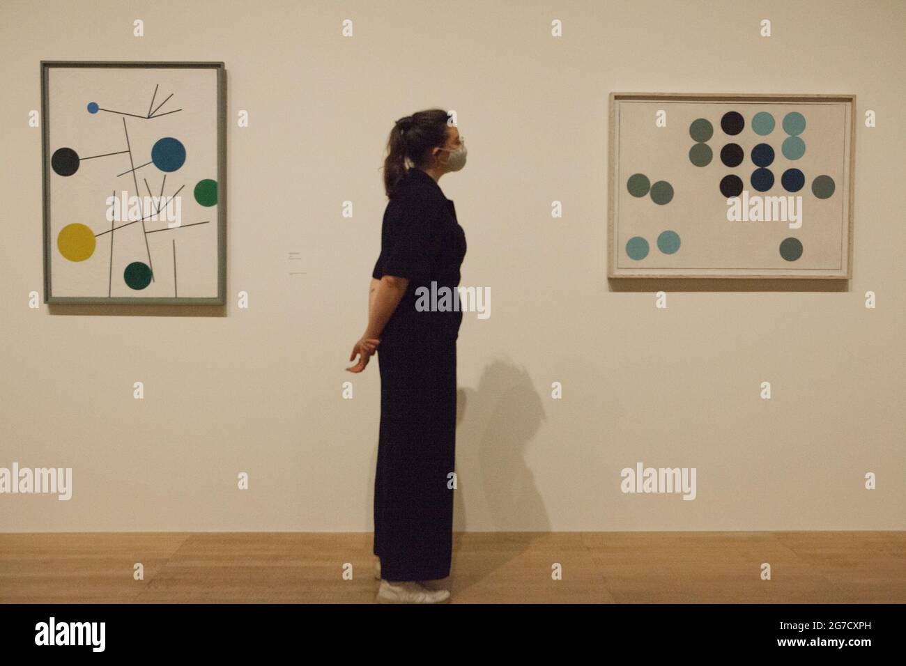 London, UK, 13 July 2021: Pioneering Swiss artist and designer Sophie Taeuber-Arp is celebrated with an exhibition at Tate Modern, opening on 15 July. Here a staff member looks at 'Aminated Circle Picture' from 1934. Sophie Taeuber-Arp (1889-1943) was a painter, craft makers, architect, interior designer, performer, jewellery maker and teacher who worked in France and Switzerland as was involved with Dadaism and abstract art in pre-war Europe. Anna Watson/Alamy Live News Stock Photo