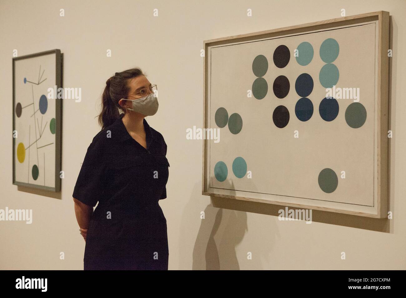 London, UK, 13 July 2021: Pioneering Swiss artist and designer Sophie Taeuber-Arp is celebrated with an exhibition at Tate Modern, opening on 15 July. Here a staff member looks at 'Aminated Circle Picture' from 1934. Sophie Taeuber-Arp (1889-1943) was a painter, craft makers, architect, interior designer, performer, jewellery maker and teacher who worked in France and Switzerland as was involved with Dadaism and abstract art in pre-war Europe. Anna Watson/Alamy Live News Stock Photo