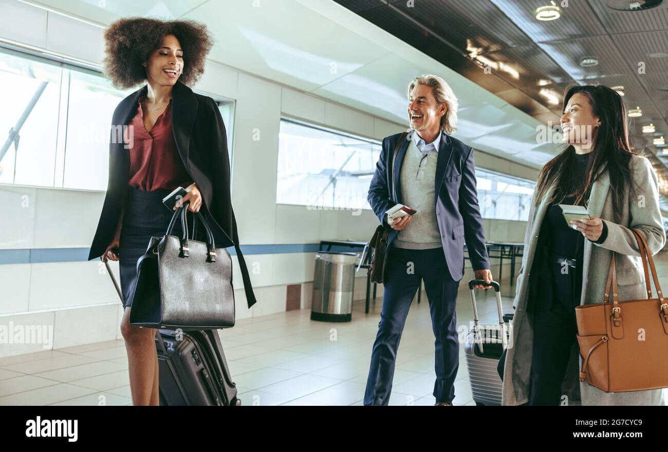 Passengers walking in the airport corridor with luggage. Smiling business people going on