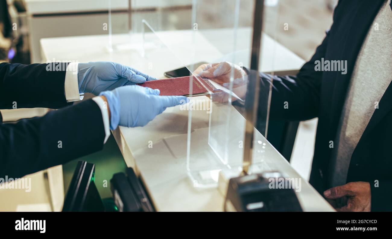 Closeup of airline check-in counter at airport. traveler giving his passport to airport staff for checking in for the flight during pandemic. Stock Photo