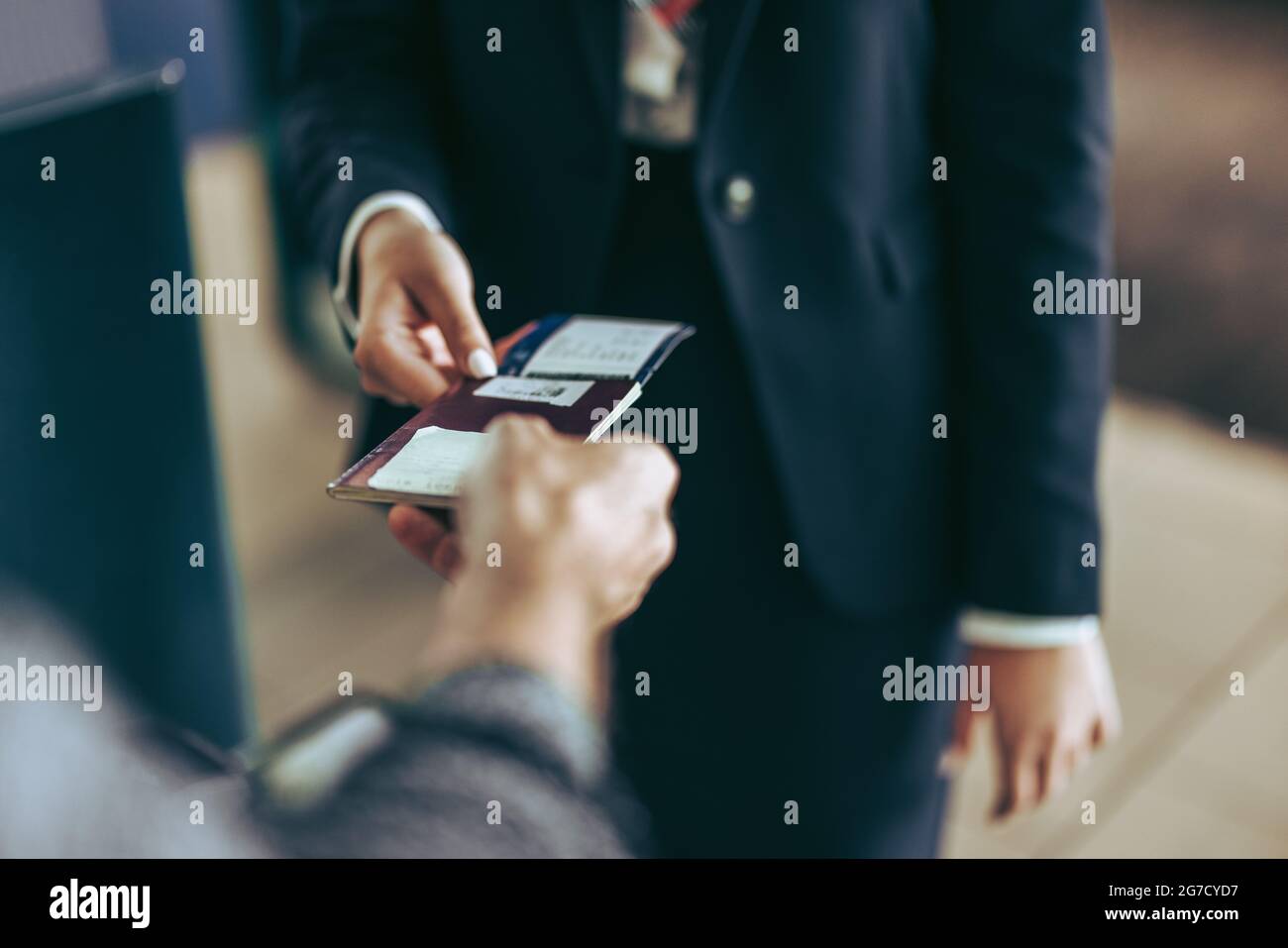 Cropped shot of airlines staff with passport of passenger at airport check-in counter. Ground staff checking passport of passenger at airport. Stock Photo