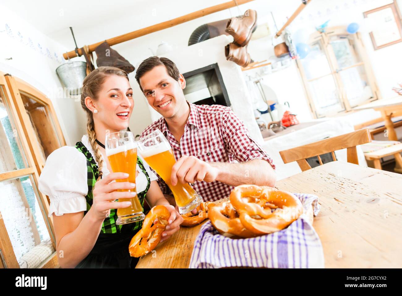 Bavarian couple wearing traditional dress, flirting and  drinking beer in restaurant Stock Photo