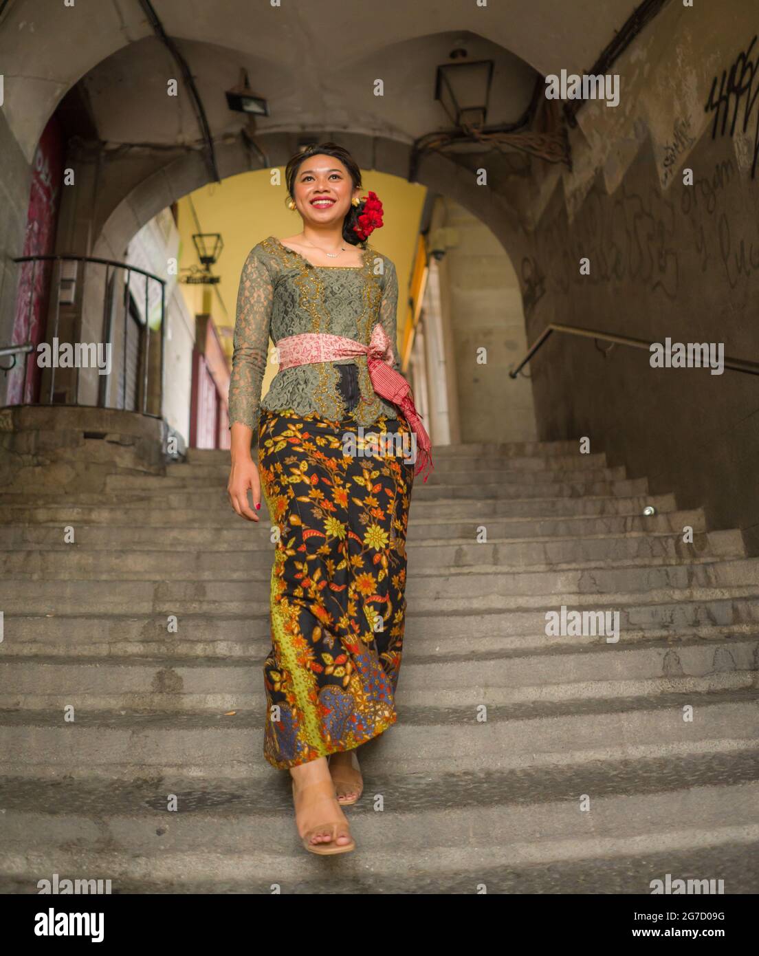 young happy and beautiful Asian woman wearing traditional Balinese kebaya dress - Indonesian girl in Bali clothes walking on street during holidays tr Stock Photo