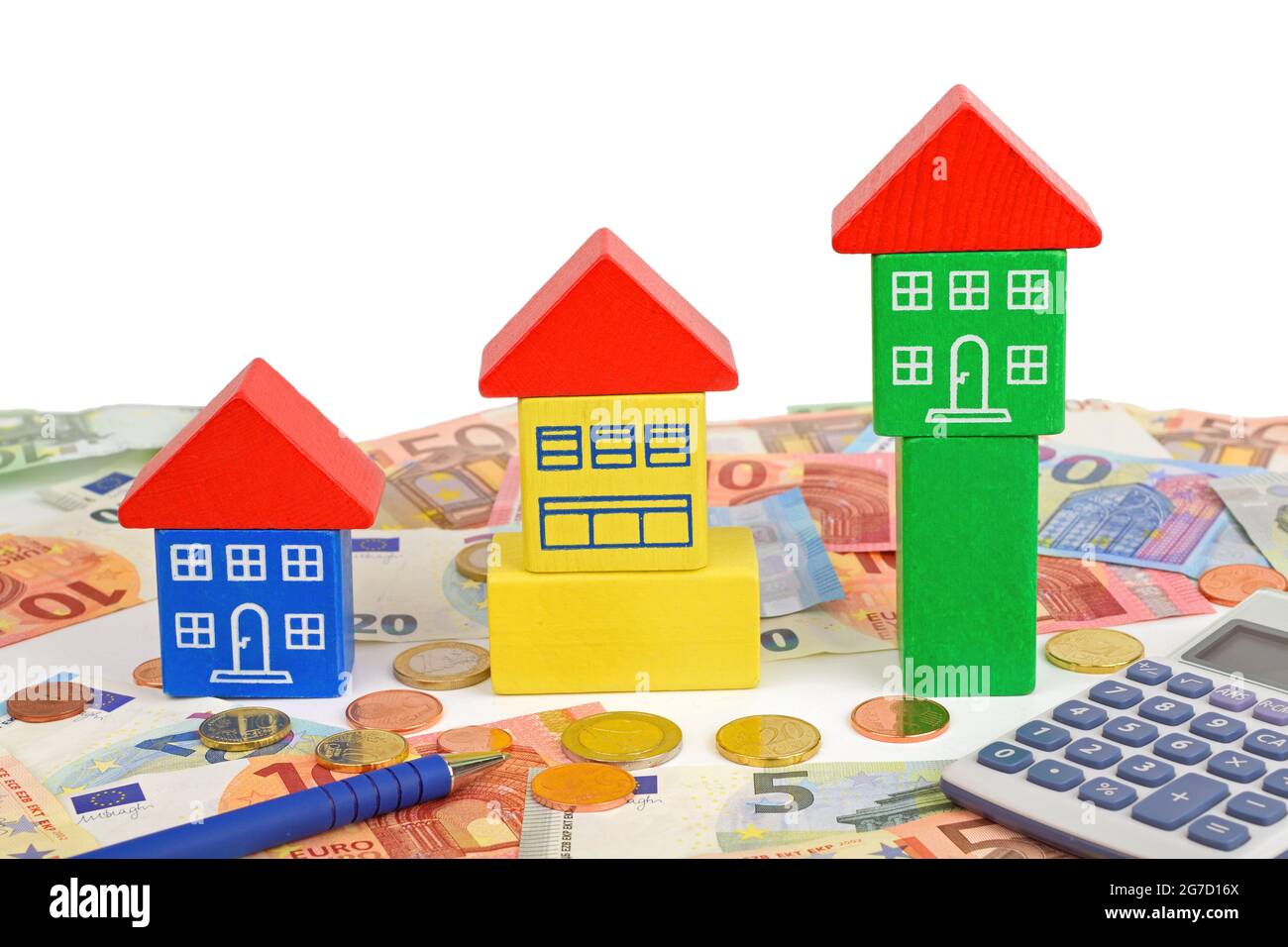 Three toy houses sitting on Euro notes and coins, with a calculator to symbolize home finance. Stock Photo