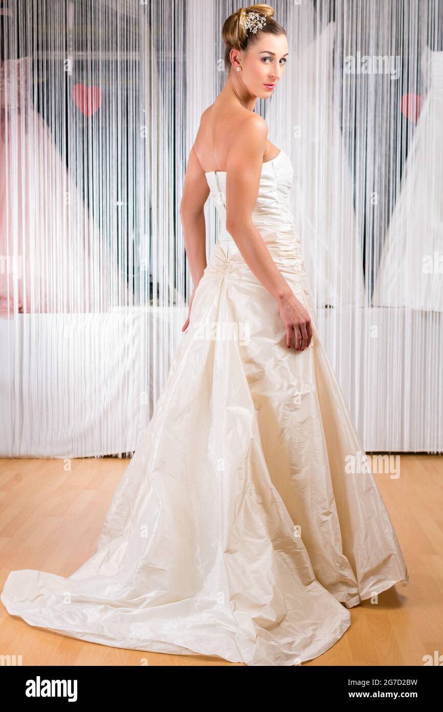 Woman trying on wedding dress or bridal gown in wedding fashion store Stock Photo