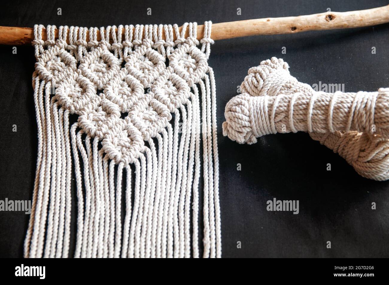 Hand woven black macrame with white beads hanging on wall Stock Photo -  Alamy
