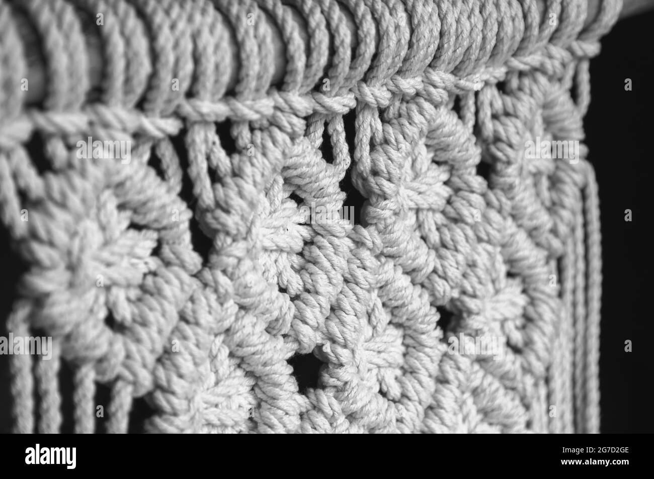 Close-up of hand made macrame texture pattern. Handmade stylish 100 cotton wall macrame decoration. Natural modern decoration concept in the interior. Stock Photo