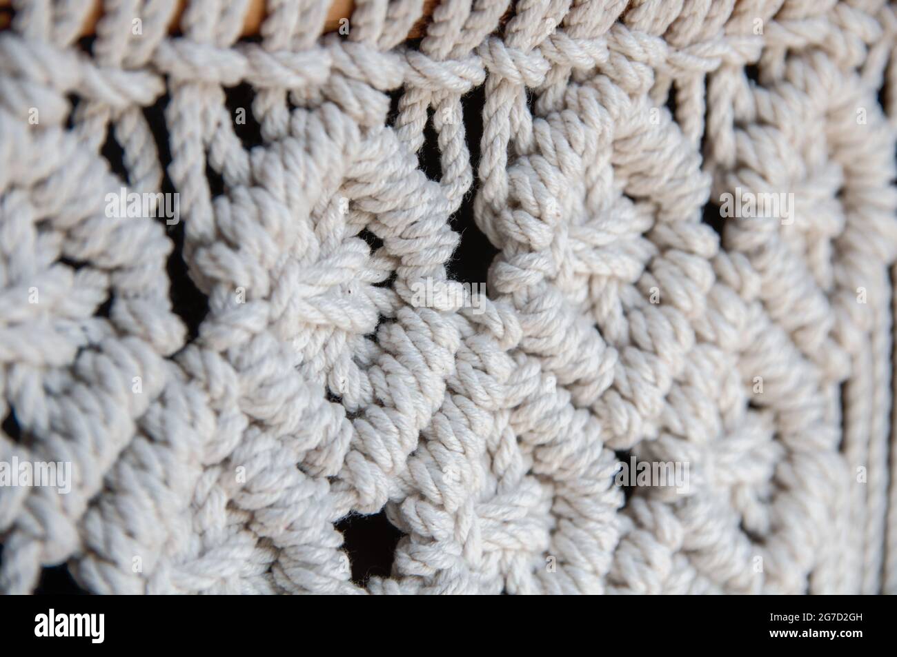 Close-up of hand made macrame texture pattern. Handmade stylish 100 cotton wall macrame decoration. Natural modern decoration concept in the interior. Stock Photo