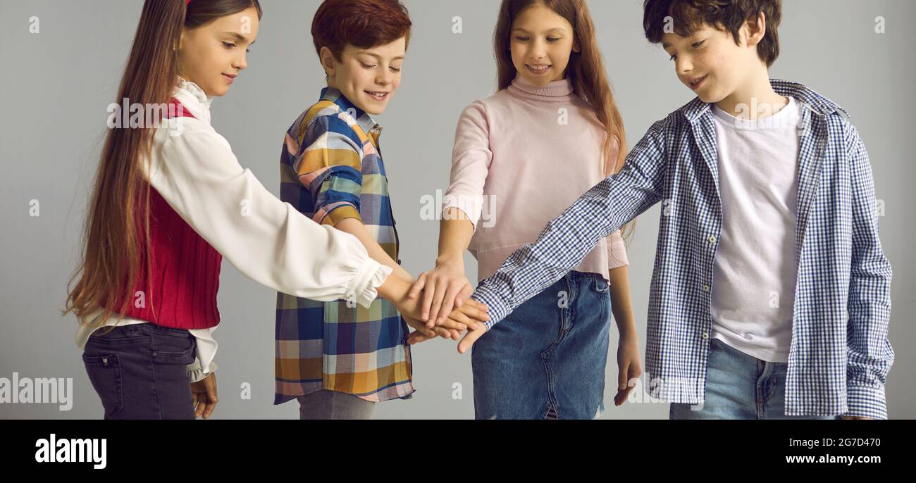 Studio group shot of four happy children standing together and joining their hands Stock Photo