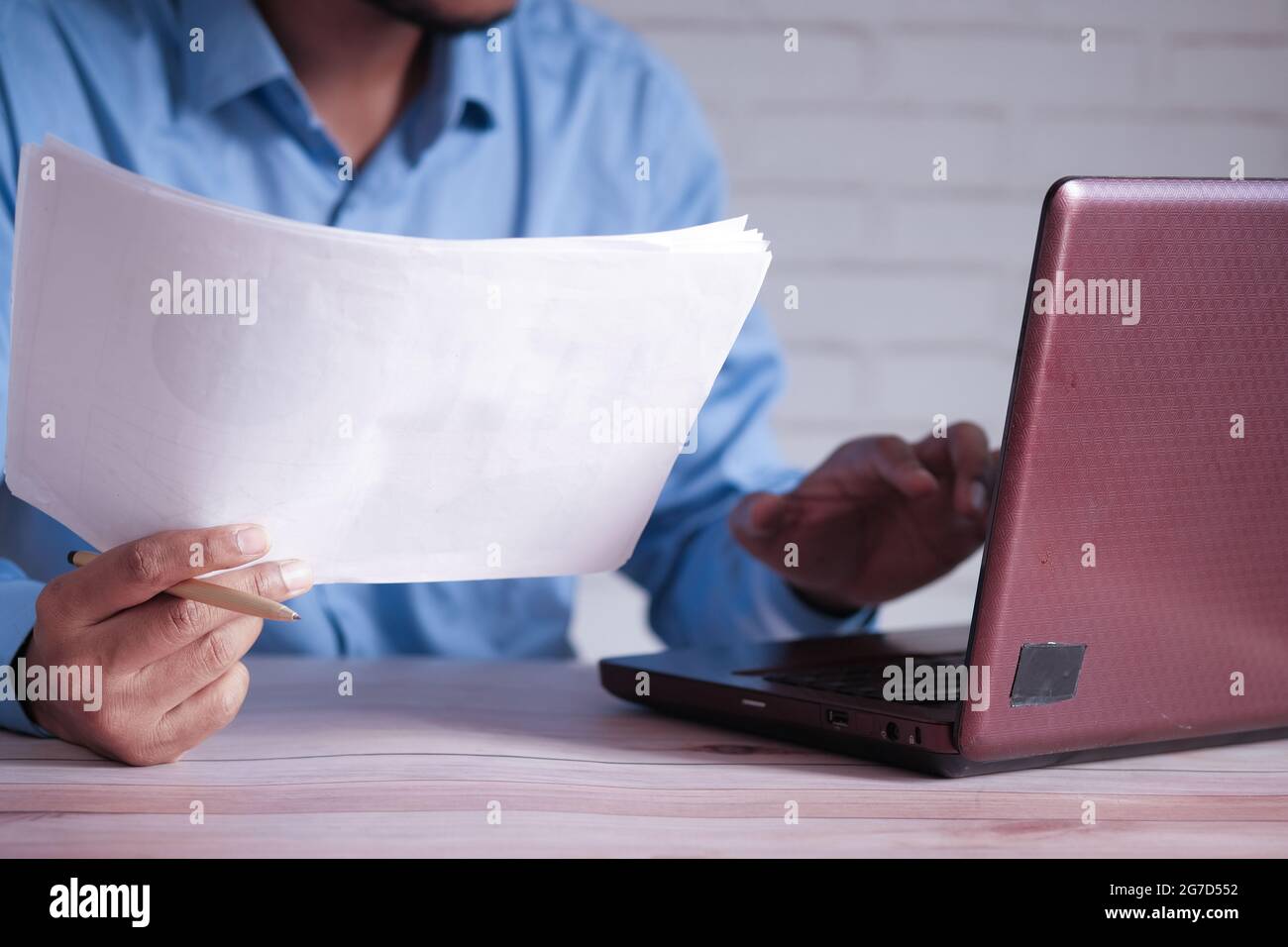 man hand with pen analyzing chart on paper while working on laptop Stock Photo