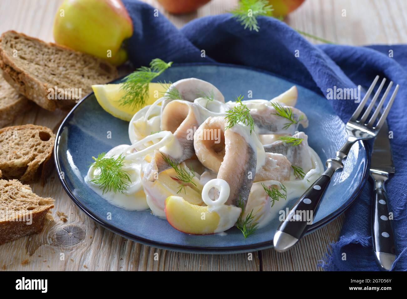 Salty herring fillets with apple slices, onion rings and yoghurt cream sauce Stock Photo