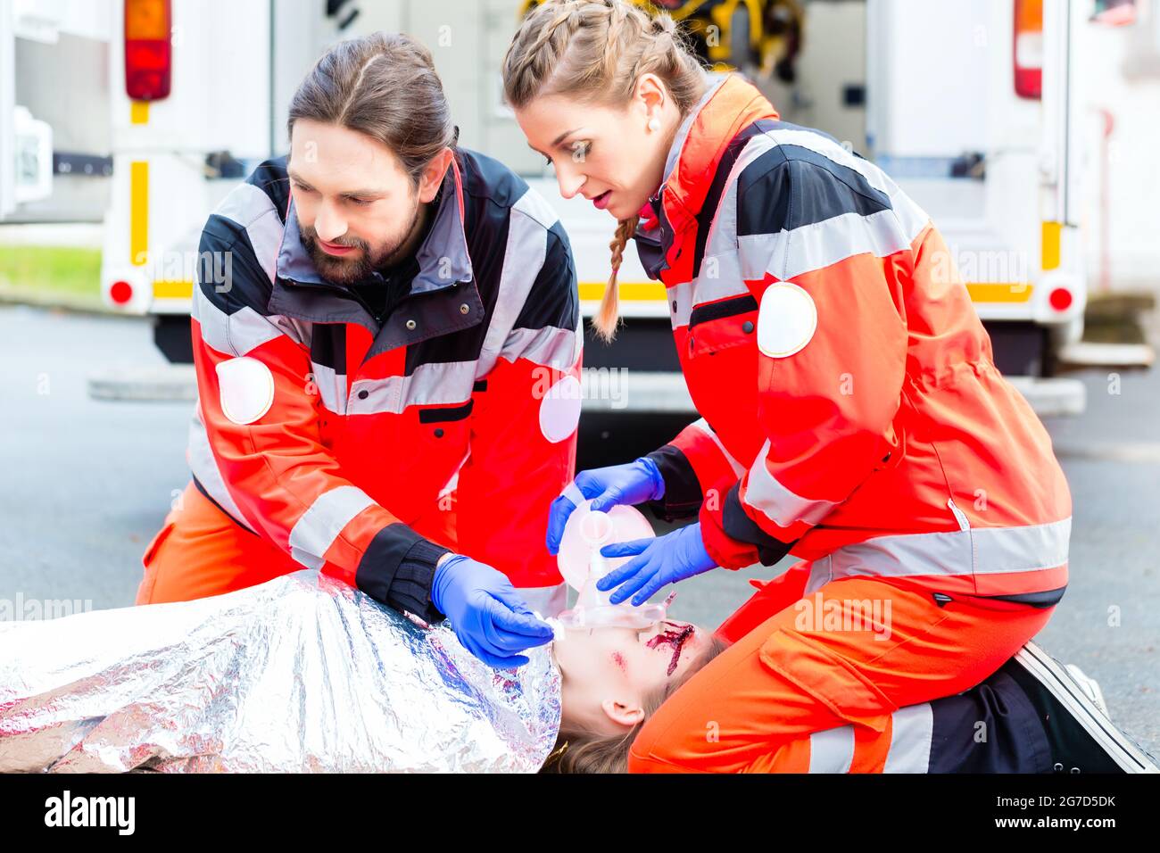 Emergency doctor and nurse or ambulance team giving oxygen to accident victim Stock Photo