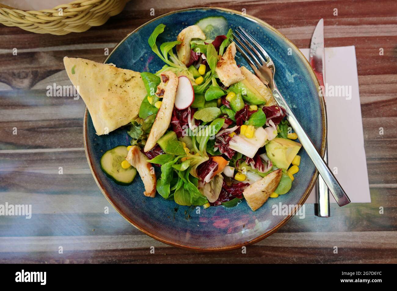 mixed salad with chicken strips and bread in a blue plate as a healthy summer meal, high angle view from above, selected focus Stock Photo
