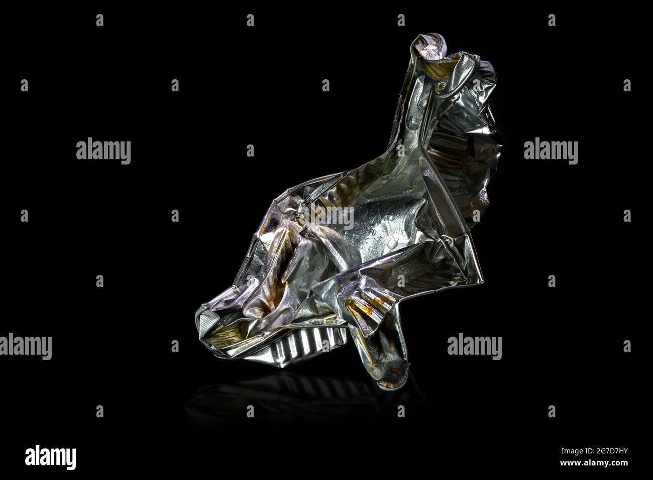 Aluminum foil tray of convenience food shown like an art sculpture against a black background, avoidable waste from disposable packaging use resources Stock Photo