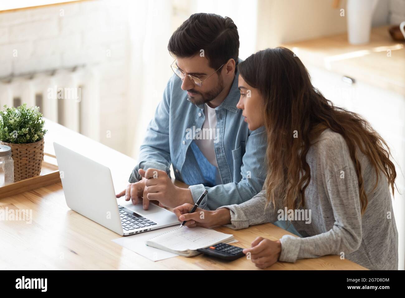 Couple looking at laptop screen analyzing expenses managing family budget Stock Photo