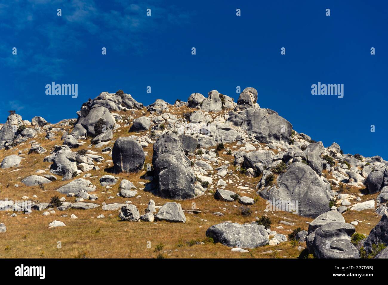 Stunning rock boulders at Castle Hill, New Zealand. Blue cloudy sky, golden grass land, surrounding mountains of the southern alps. Arthur's pass Stock Photo