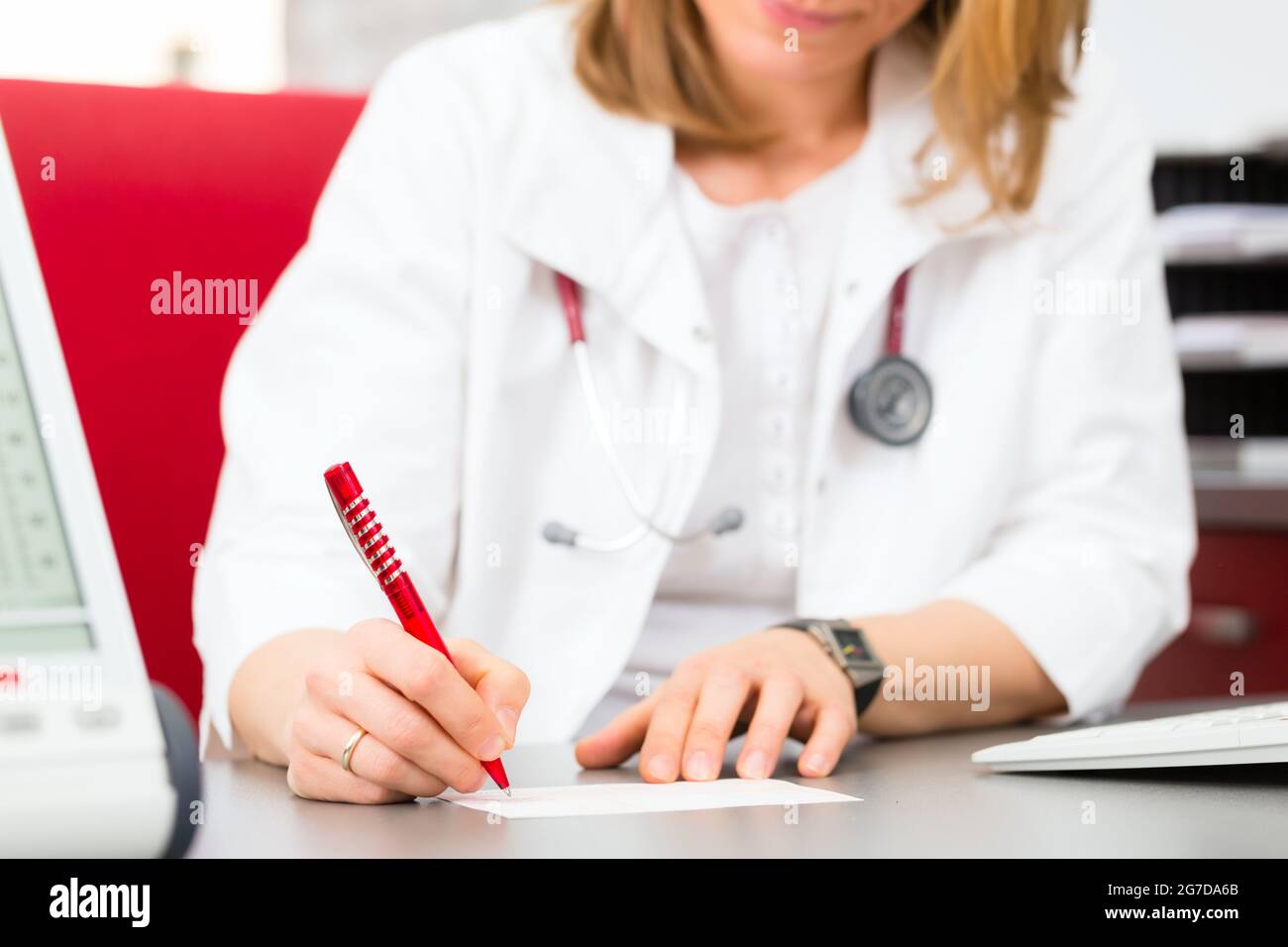 Young gynaecologist writing medical prescription in surgery at desk ...