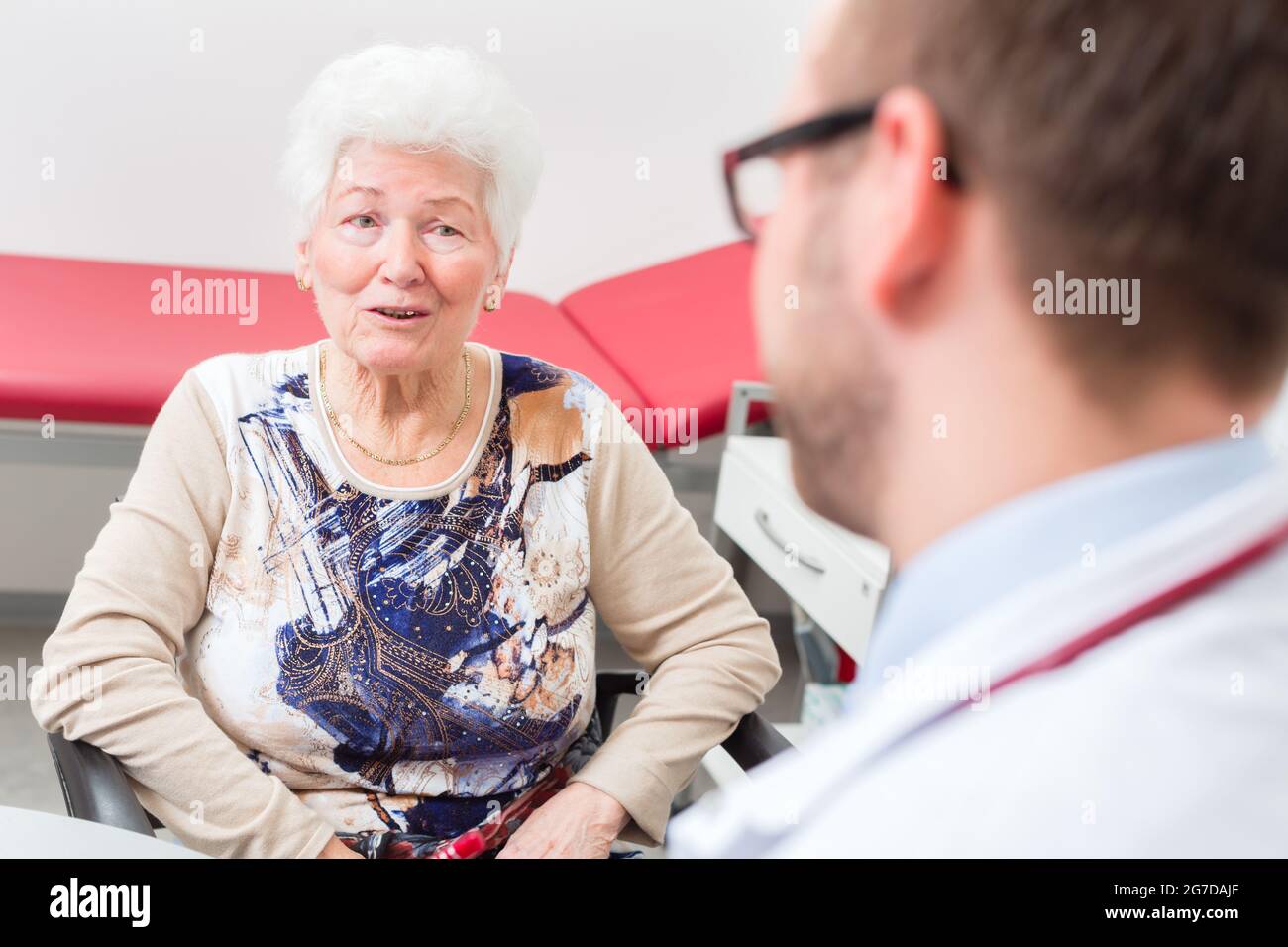 Doctor sitting with pensioner in surgery consultation hour at desk Stock Photo