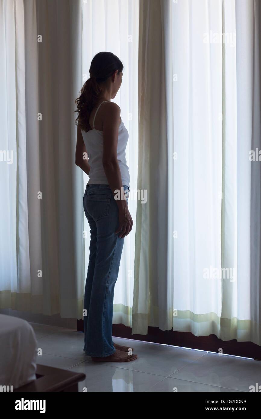 Silhouette of woman standing by a window Stock Photo