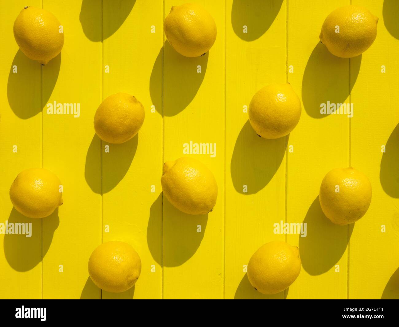 Ripe lemons on the yellow wooden surface, top view. Vibrant background Stock Photo
