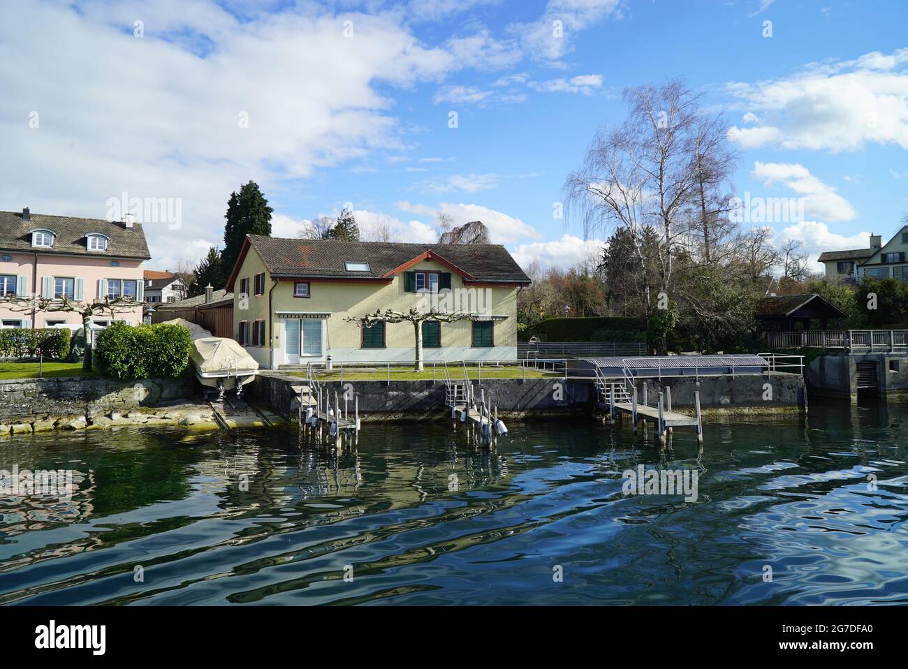 Lake surrounded by houses and greenery under a blue cloudy sky Stock ...