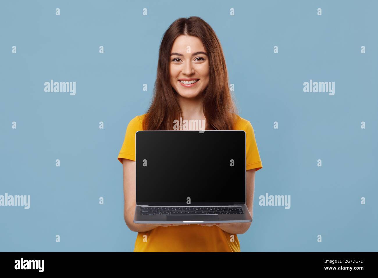 Pretty young lady showing laptop with empty screen Stock Photo