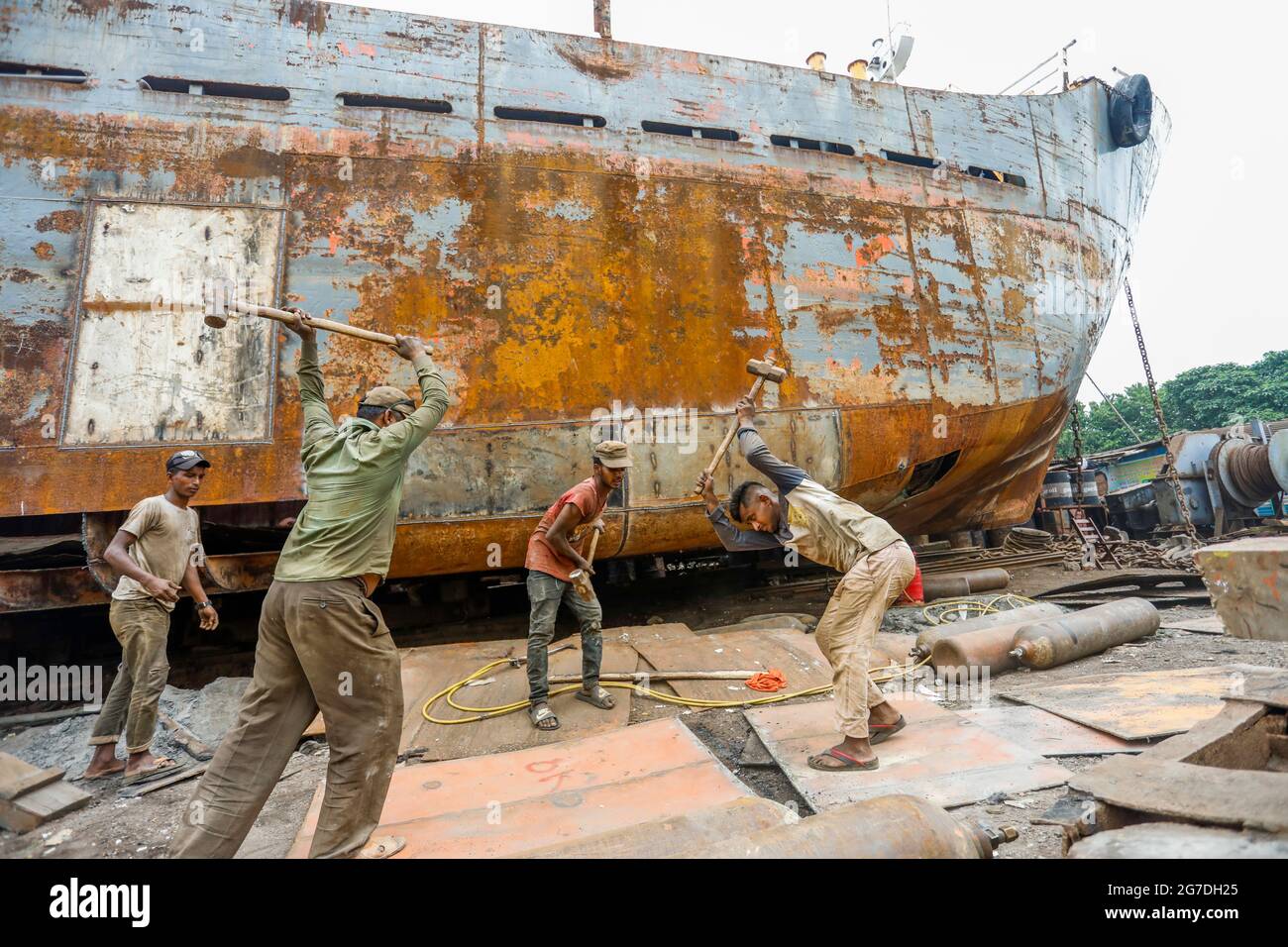 Bangladeshi workers repair a vessel at a dockyard on the bank of River Buriganga, in Keraniganj, near Dhaka, Bangladesh, July 13, 2021. With an increa Stock Photo
