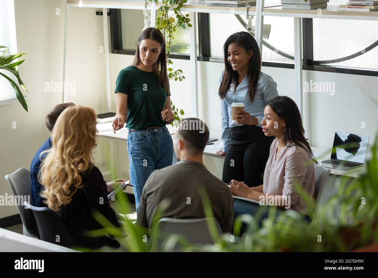 Millennial business team meeting and talking, discussing work project Stock Photo