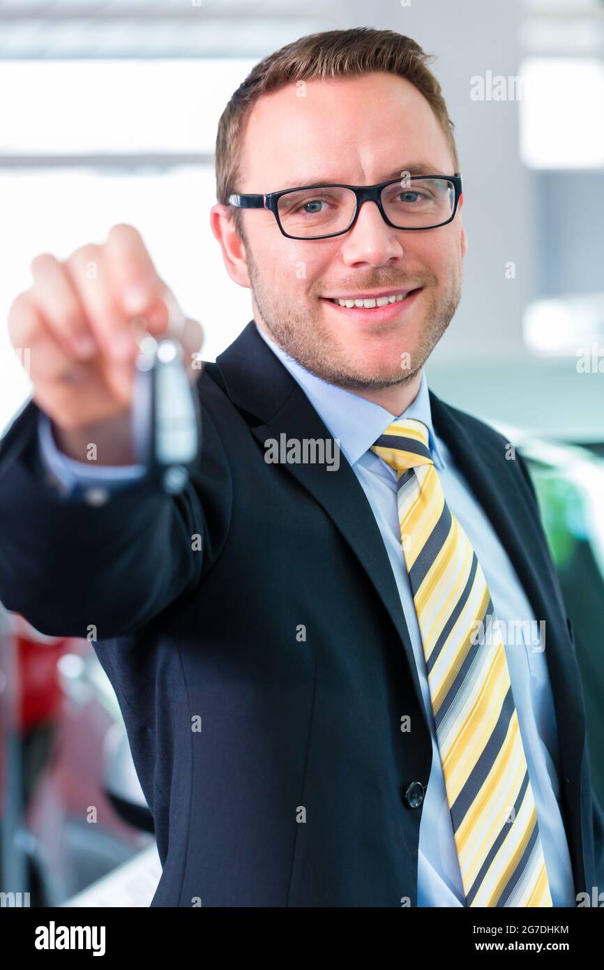 Salesman handing over auto key at car dealership Stock Photo Alamy