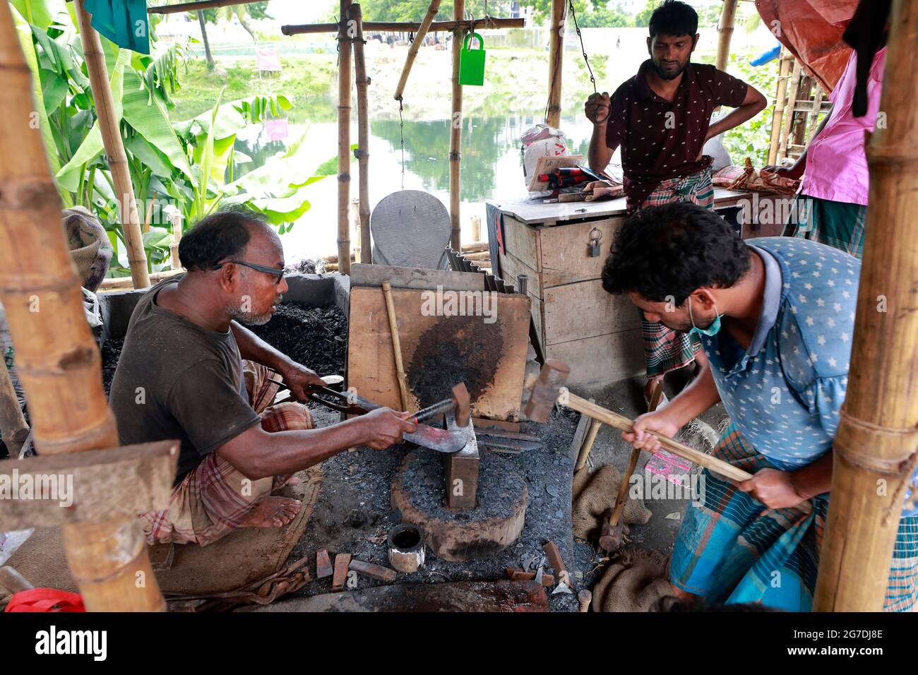 Dhaka, Bangladesh - July 13, 2021: Blacksmith makes knives at Rampura market in Dhaka. Bangladeshi Muslim People will be used to slaughter sacrificial Stock Photo