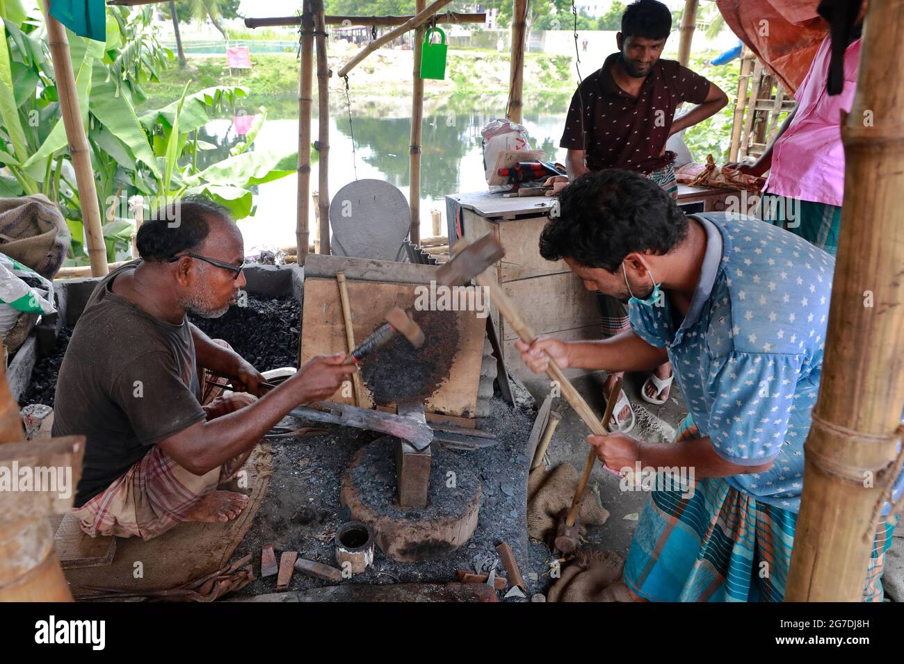 Dhaka, Bangladesh - July 13, 2021: Blacksmith makes knives at Rampura market in Dhaka. Bangladeshi Muslim People will be used to slaughter sacrificial Stock Photo