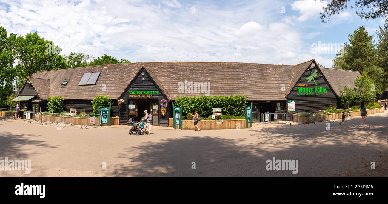 Parents and children walking past Visitor centre and refreshments at Moors Valley Country Park on a sunny summers day with light cloud. Stock Photo