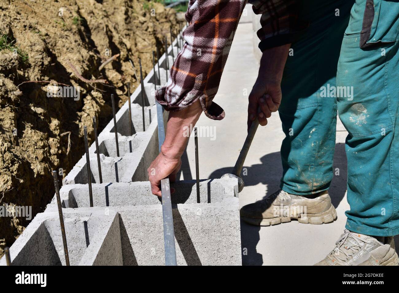 Mason Using Blocks The mason places and prefabricated blocks into the wall at home on the ...