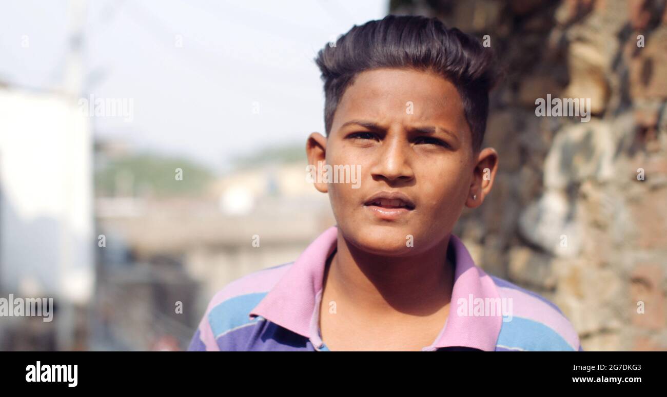 Closeup of a young Indian boy with an earring in one ear looking confused into the camera Stock Photo