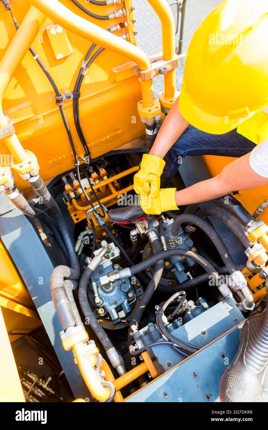 Asian motor mechanic working on construction or mining machinery in ...